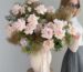 Anita Dudutite, founder of TheFlow, with a tall arrangement of garden roses, smoke bush and clematis