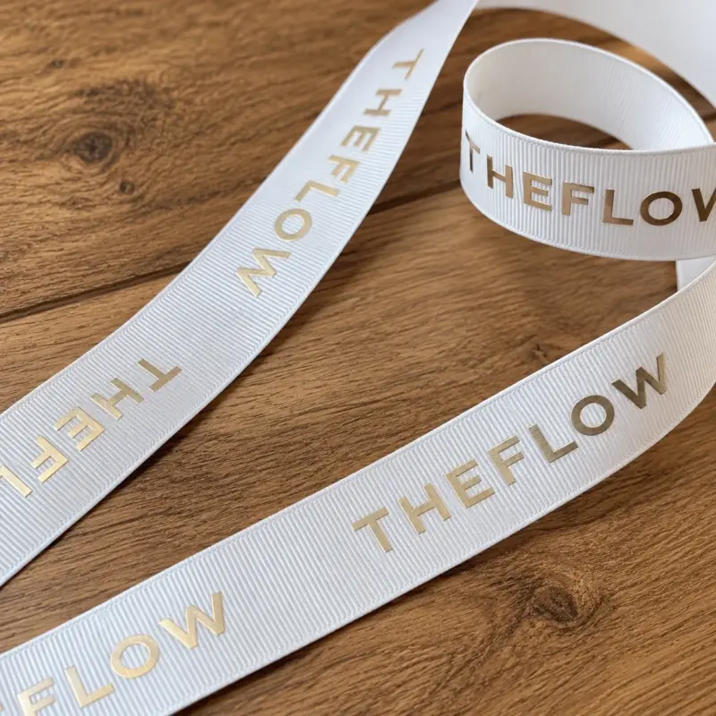 White TheFlow ribbon with the THEFLOW logo in foil