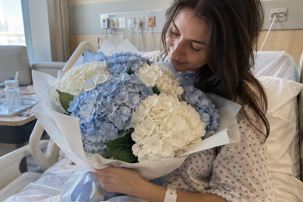 New mom in a hospital bed hugging a blue and white hydrangea bouquet