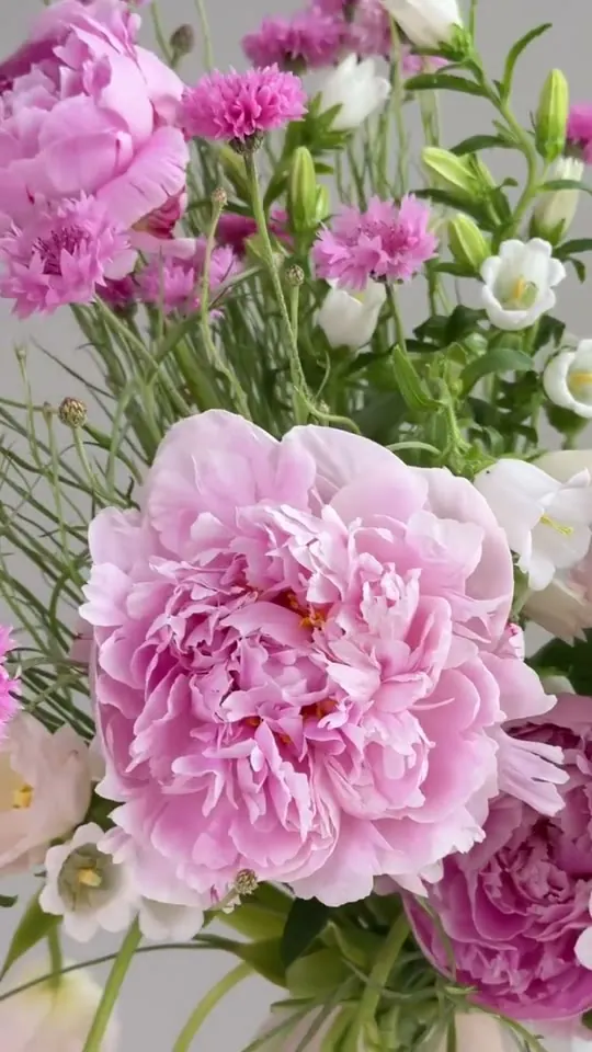 TheFlow florist arranging peonies and garden flowers in a vase in the studio